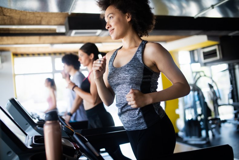 Image of a woman smiling while running on a treadmill at the gym